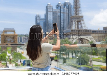 Woman use cellphone to take photo of Macau city downtown 
