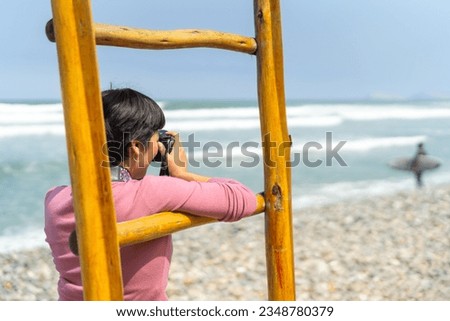 Rear view of a female freelance photographer taking pictures on the beach