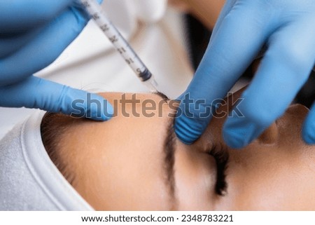Young woman getting injection between the eyebrows to remove wrinkles in cosmetic salon. Rejuvenation therapy.  Royalty-Free Stock Photo #2348783221