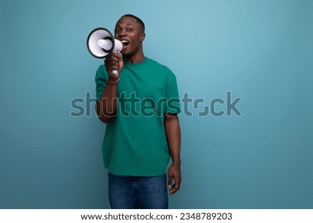 a young handsome african guy with a short haircut wearing a basic t-shirt speaks using a microphone to get attention