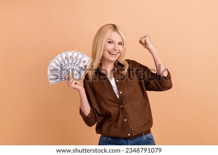 Photo of funny elderly lady raise fist up celebrate her lottery jackpot easy money betting igaming isolated on beige color background