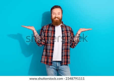 Portrait of handsome man brutal red hair beard holding arms balance presentation two products comparing isolated on blue color background