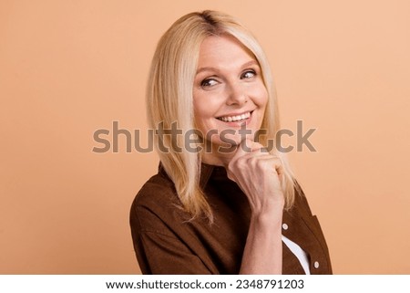 Closeup portrait of attractive model middle age woman touch chin thoughtful looking empty space isolated on beige color background