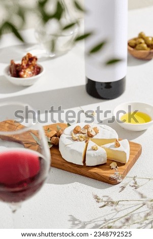 Delicious Camembert cheese on a wooden board, paired with a bottle and glass of red wine. Perfect for food and wine articles or advertisements. Trendy, natural, and vertical composition.