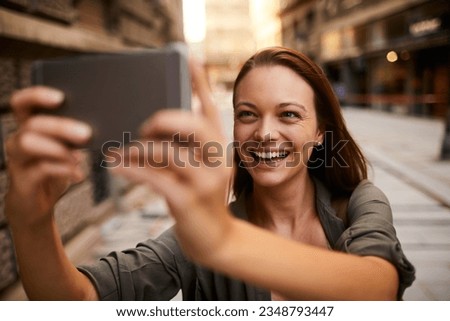 Young caucasian woman taking a picture with her smart phone while on a sidewalk in the city