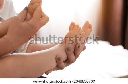 Mothers day. Smiling young mother playing with baby girl boy legs on bed at home bedroom. Loving mom enjoying caring and educating little child. Healthy childcare. Maternity Parenthood Motherhood