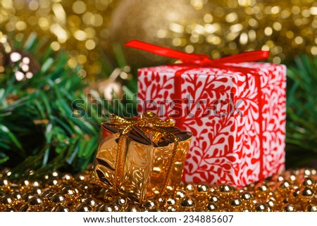 Christmas present boxes with yellow beads with green fir-tree branch on background