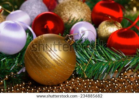 Red, white and yellow christmas balls lying on green fir-tree branch