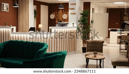 Wide angle shot of travel accommodation hotel lounge with check in reception desk. Stylish empty modern resort foyer interior with cozy furniture and warm fireplace ready to welcome tourists Royalty-Free Stock Photo #2348867111