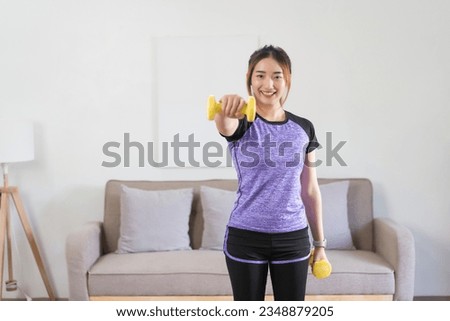 Young asian woman doing exercise and lifting dumbbells to workout training strong arms in home. Royalty-Free Stock Photo #2348879205
