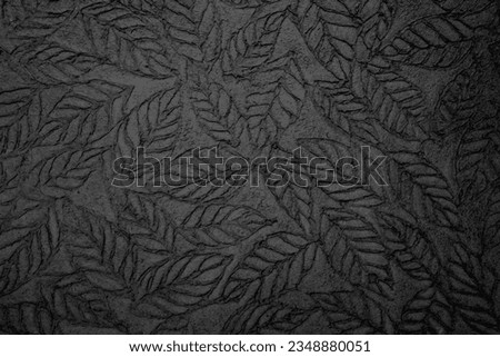Leaf pattern stamped on chalkboard texture, handmade black background.