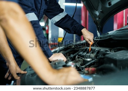 Team of vehicle technicians checking and measuring a vehicle oil engine or engine lubricant level by using oil stick indicator. Senior professional repairman inspecting an oil engine in an old car. Royalty-Free Stock Photo #2348887877