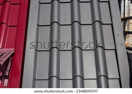 Photo of gray and red metal tile. Roof covering. Construction Materials.