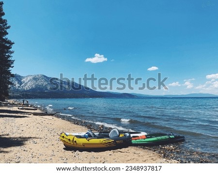 Inflatable boats on Lake Tahoe beach in summer with mountain views and white clouds on the horizon