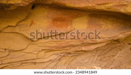 Ancient pictograph panel with depictions of deer and pronghorn that have been worn away by natural weathering and layers of sandstone breaking away.  Royalty-Free Stock Photo #2348941849
