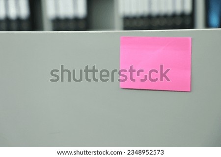 Blank pink sticky note attached to the office desk, stock photo