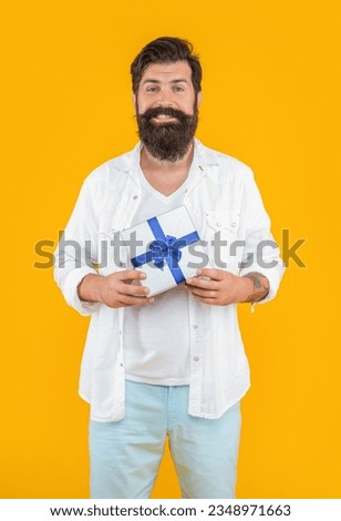 happy bearded man offer sale gift isolated on yellow. man offer sale gift in studio.