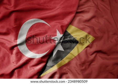 big waving national colorful flag of turkey and national flag of east timor . macro