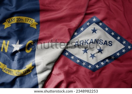 big waving colorful national flag of arkansas state and flag of north carolina state . macro