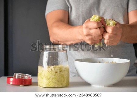 Unrecognizable man draining cabbage to prepare homemade sauerkraut or fermented cabbage. Royalty-Free Stock Photo #2348988589
