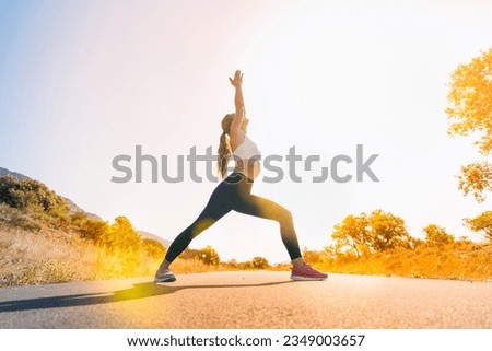 young woman doing yoga in nature on sunrise road- sport,flexibility,active lifestyle,stretching, yoga concept