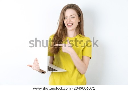 Shocked Young woman wearing yellow T-shirt pointing finger modern device