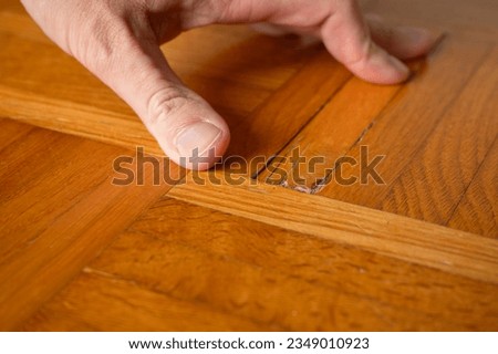 Old damaged parquet with loose strips (strip parquet) is examined by a specialist before it is reconditioned by re-sanding. Royalty-Free Stock Photo #2349010923