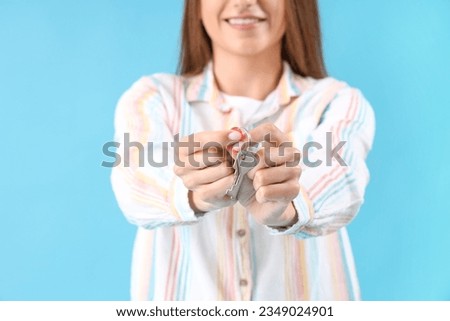 Young woman with keys from house on blue background, closeup