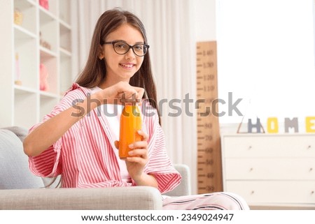 Little girl with bottle of juice at home