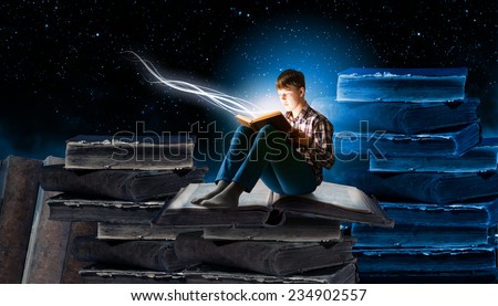 Teenager boy in jeans and shirt reading book