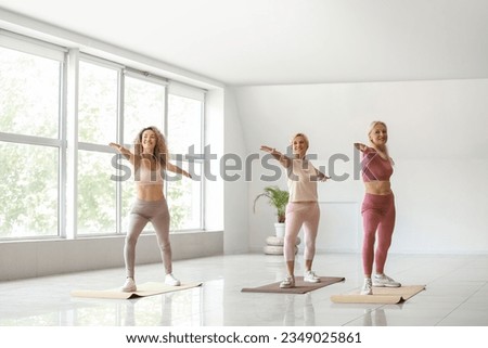 Sporty mature women practicing yoga in gym Royalty-Free Stock Photo #2349025861