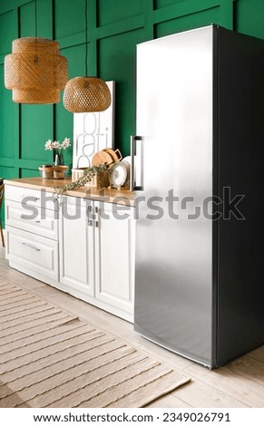 Interior of kitchen with stylish fridge, counters, lamps and picture
