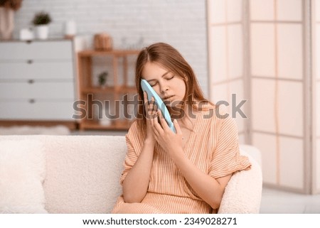 Young woman with tooth ache holding cold compress at home Royalty-Free Stock Photo #2349028271