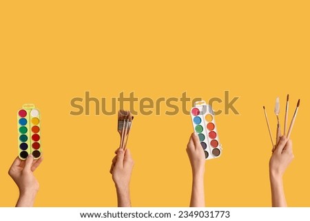 Female hands with artist's supplies on yellow background