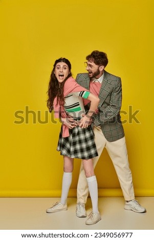 cheerful couple having fun, man in glasses and young woman with open mouth, excited, student outfits