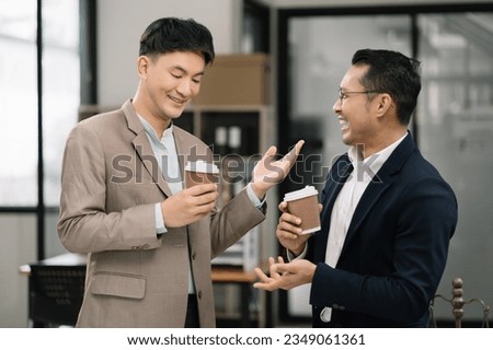 male colleague during work break standing holding coffee mugs in work area smiling various business team talking joyfully enjoying conversation friendly relations in the office.