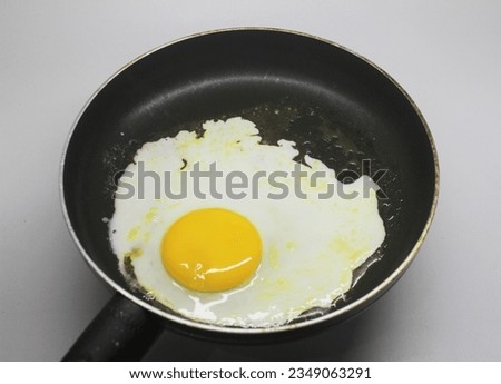 Fried sunny side up egg with yellow yolk in a black teflon. The picture was taken in a kitchen, in Indonesia, East Java.
