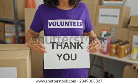 Middle age hispanic woman volunteer holding thank you message at charity center