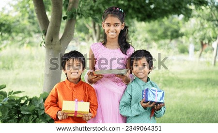 Indian good looking little brother and sister celebrating Raksha Bandhan festival or on Bhai dooj with Poja Thali, sweets, gifts or taking selfie pictures - Season's Greeting Card