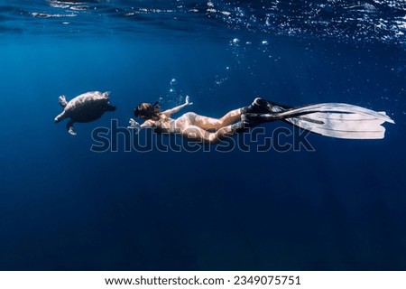 Lady with fins snorkeling underwater with turtle in ocean. Swimming with sea turtle.