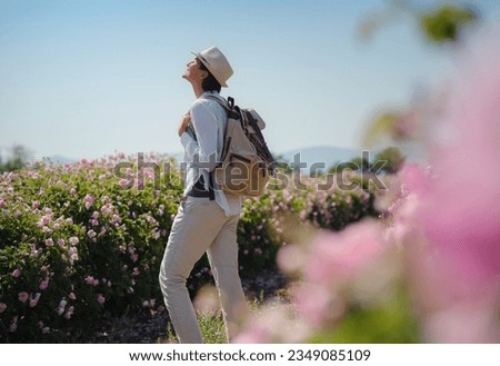 woman enjoying the aroma in Field of Damascena roses in sunny summer day . Rose petals harvest for rose oil perfume production. village Guneykent in Isparta region, Turkey a real paradise for eco Royalty-Free Stock Photo #2349085109