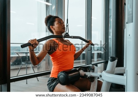 Dedicated serious fit woman with sweat doing exercises, working out on Lat pulldown machine in fitness gym, strengthening back muscles. Strong and healthy concept. Royalty-Free Stock Photo #2349087045
