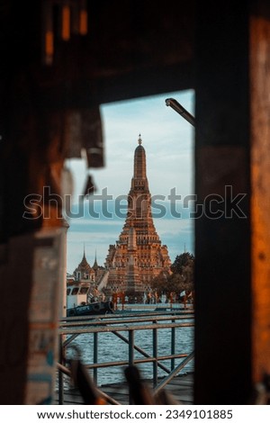 Wat Arun Ratchawararam Temple through this captivating photograph captured from a window frame across the Chao Phraya River.