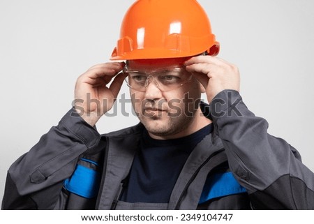 Portrait of a handsome worker builder in overalls, helmet and glasses on a white background. Royalty-Free Stock Photo #2349104747