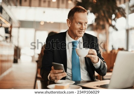 Mature businessman using a smart phone and enjoying a coffee at an indoor cafe