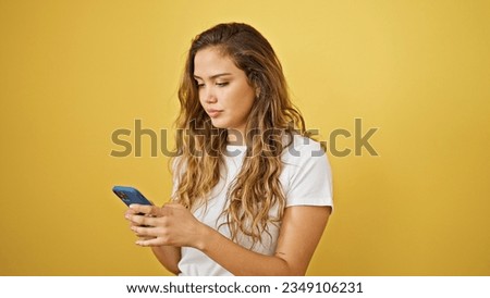 Young beautiful hispanic woman using smartphone with serious expression over isolated yellow background