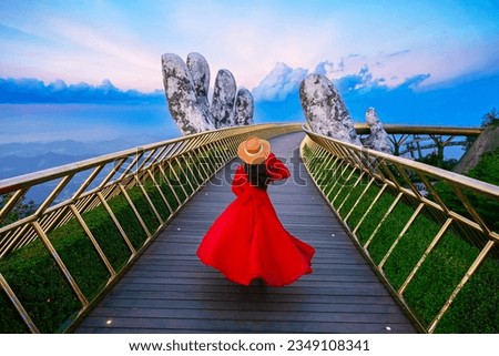 Female tourists having fun and relaxing on the golden bridge two giant hands in the tourist resort on Ba Na Hill in Da Nang, Vietnam. Royalty-Free Stock Photo #2349108341