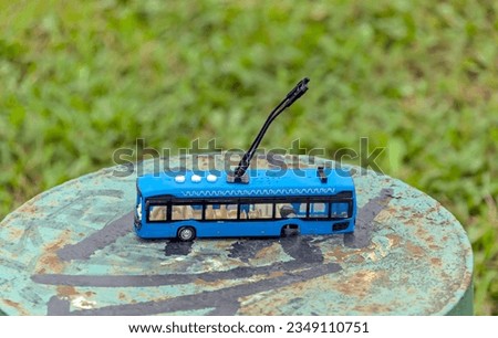 
On a steel pipe there is a toy trolleybus without rear wheels