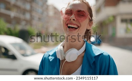 Young woman wearing heart sunglasses and headphones at street