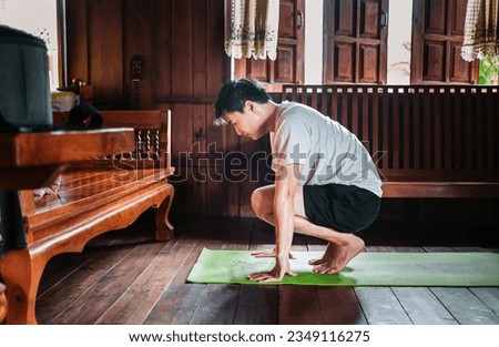 Asian men practice yoga in different poses while exercising on a yoga mat at home with a wooden floor. Man Yoga Practice Pose Training Healthy Living Concept